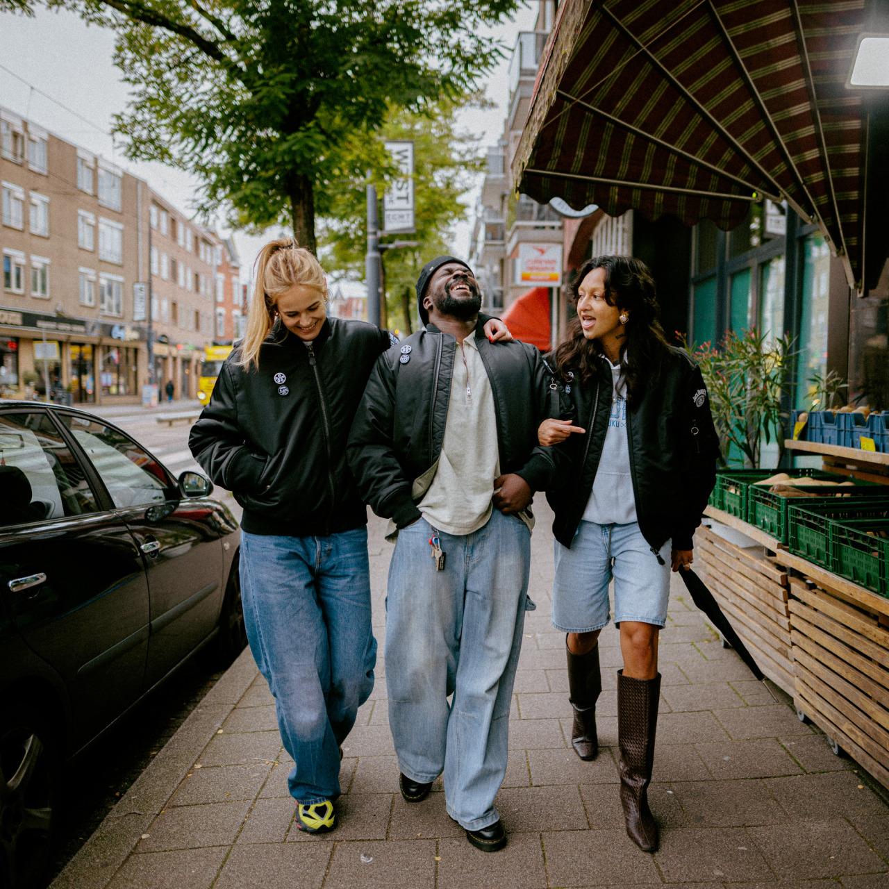 Drie vrienden lopen lachend door een stadsstraat